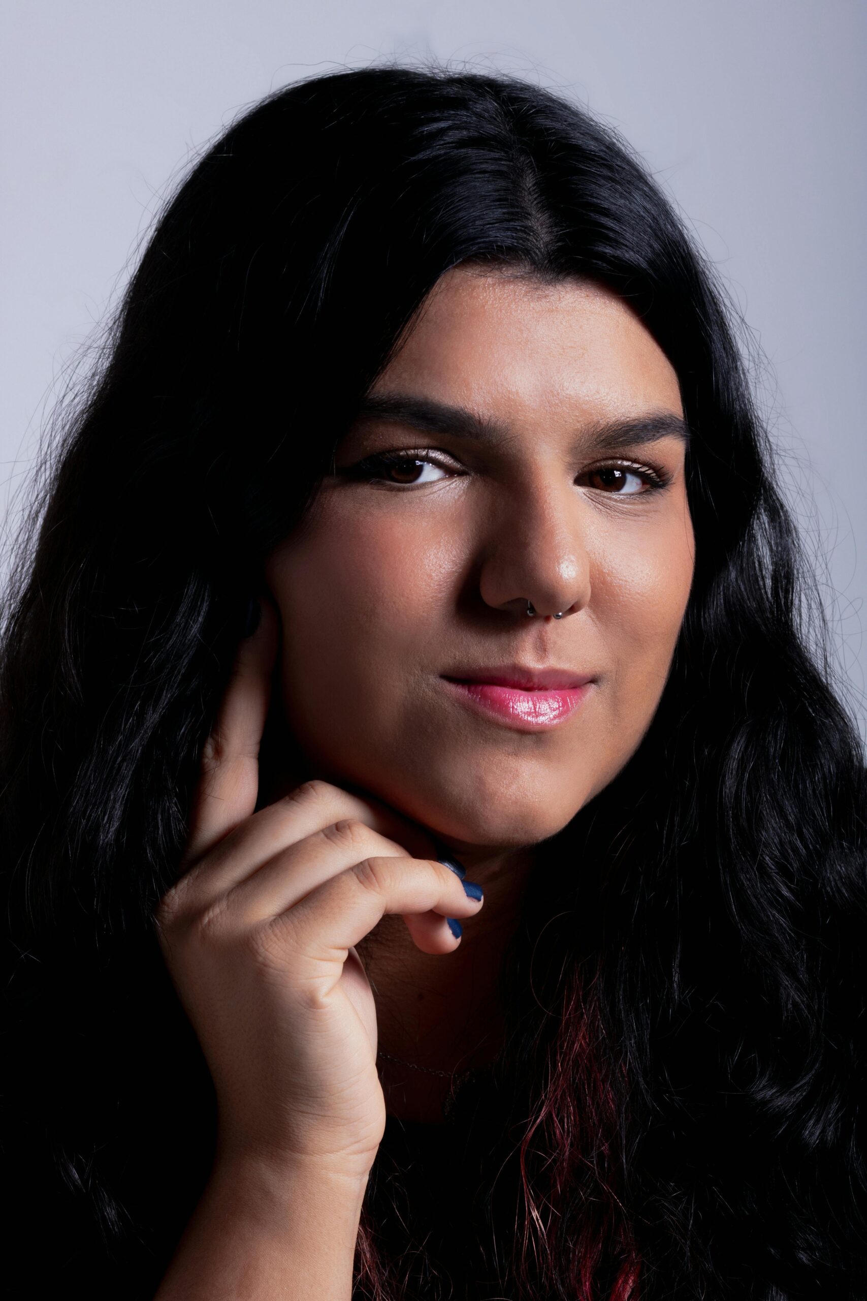 Close-up portrait of a woman with long dark hair and elegant pose in a studio setting.